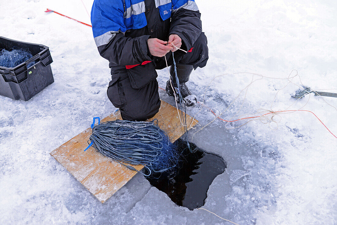 Fisherman practicing ice fishing in Lake Inari, Lapland, Finland