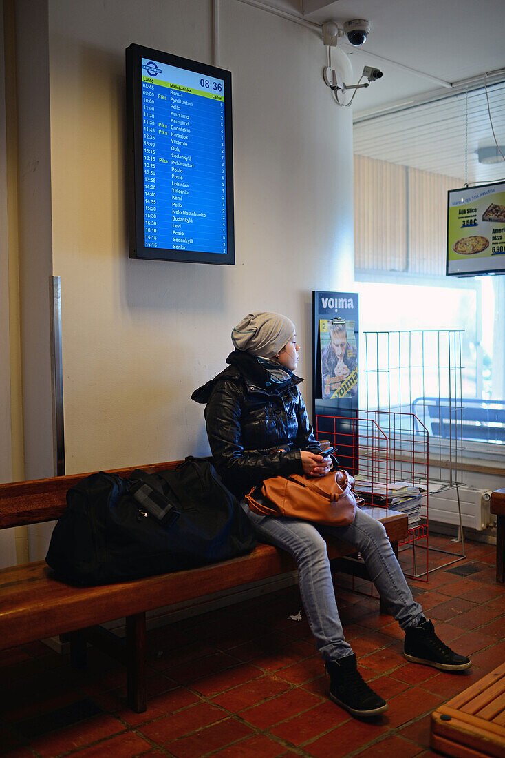 Junge Frau wartet am Busbahnhof in Rovaniemi auf den Bus