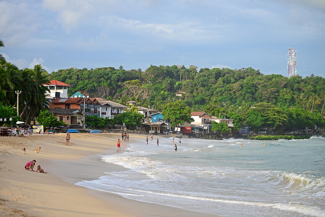 Locals and tourists enjoying a sunny day on Unawatuna beach in Galle district, Sri Lanka