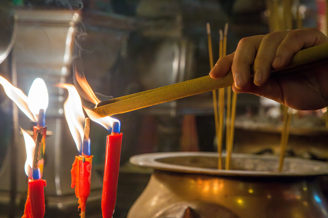 Ein Gläubiger entzündet Räucherstäbchen oder Weihrauch im buddhistischen Man-Mo-Tempel in Hongkong, China