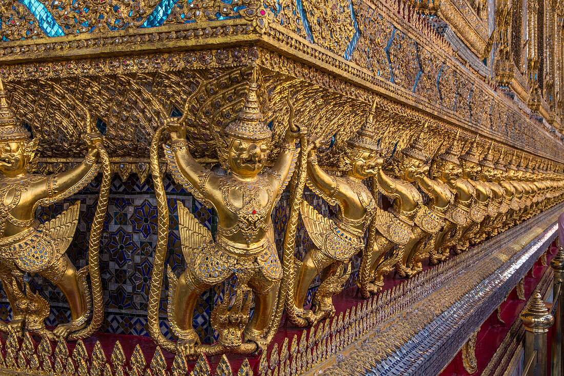 Golden statues of Garuda vs. the naga guards the Temple of the Emerald Buddha in the Grand Palace complex in Bangkok, Thailand.