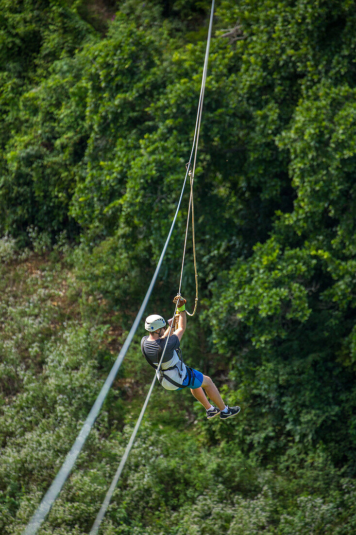 Ein Mann beim Ziplining über dem Regenwald bei Sosua in der Dominikanischen Republik