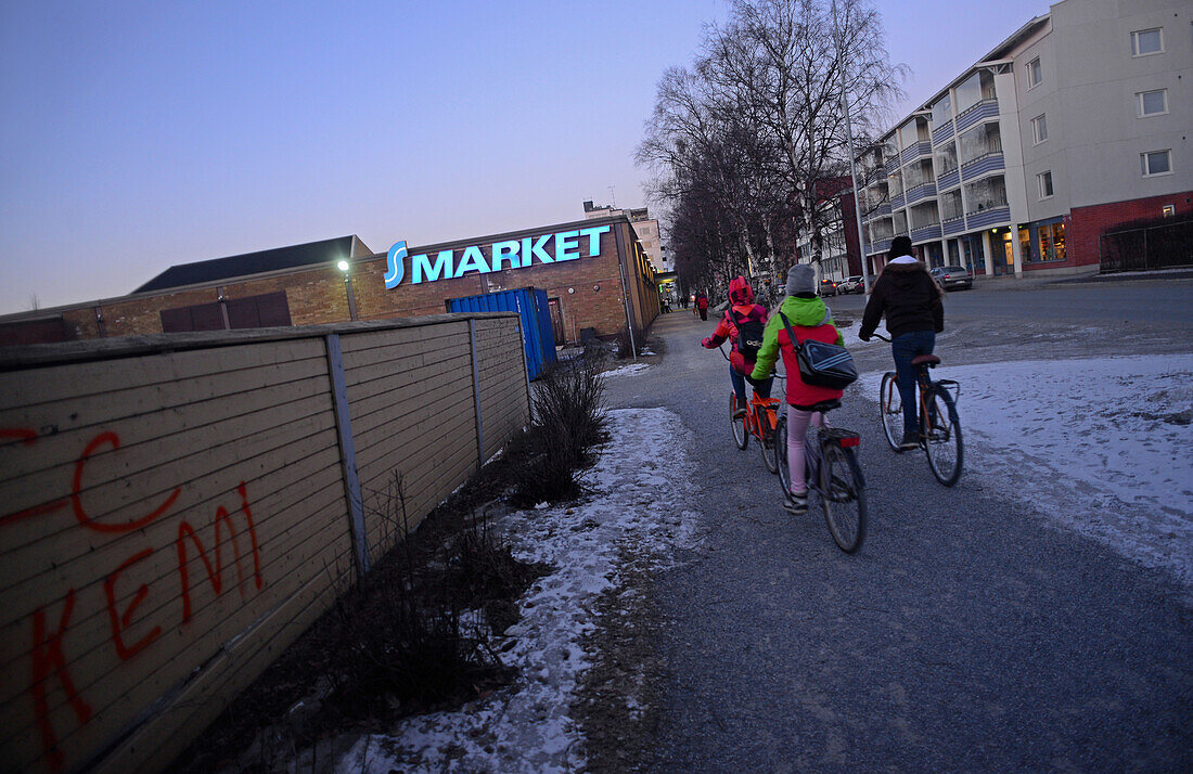 Kinder fahren Fahrrad bei Sonnenuntergang in Kemi, Lappland