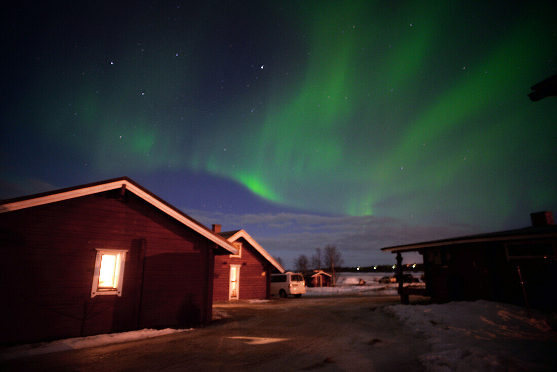 Aurora Borealis (Nordlicht) über VisitInari-Holzhütten im Inari-See, Lappland, Finnland