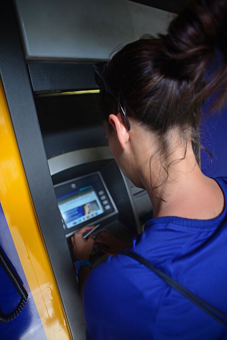 Junge kaukasische Frau benutzt einen Geldautomaten in Matale, Sri Lanka