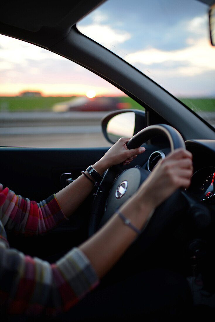 Young woman driving car at sunset