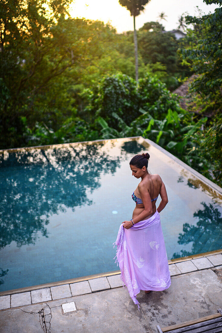 Young attractive woman enters an infinity edge swimming pool at The Dutch House, Galle, Sri Lanka