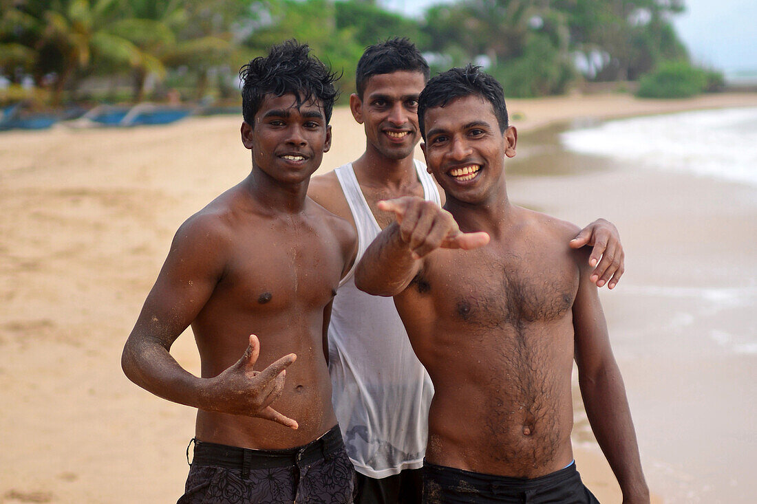 Drei junge Männer am Strand von Hikkaduwa, Sri Lanka