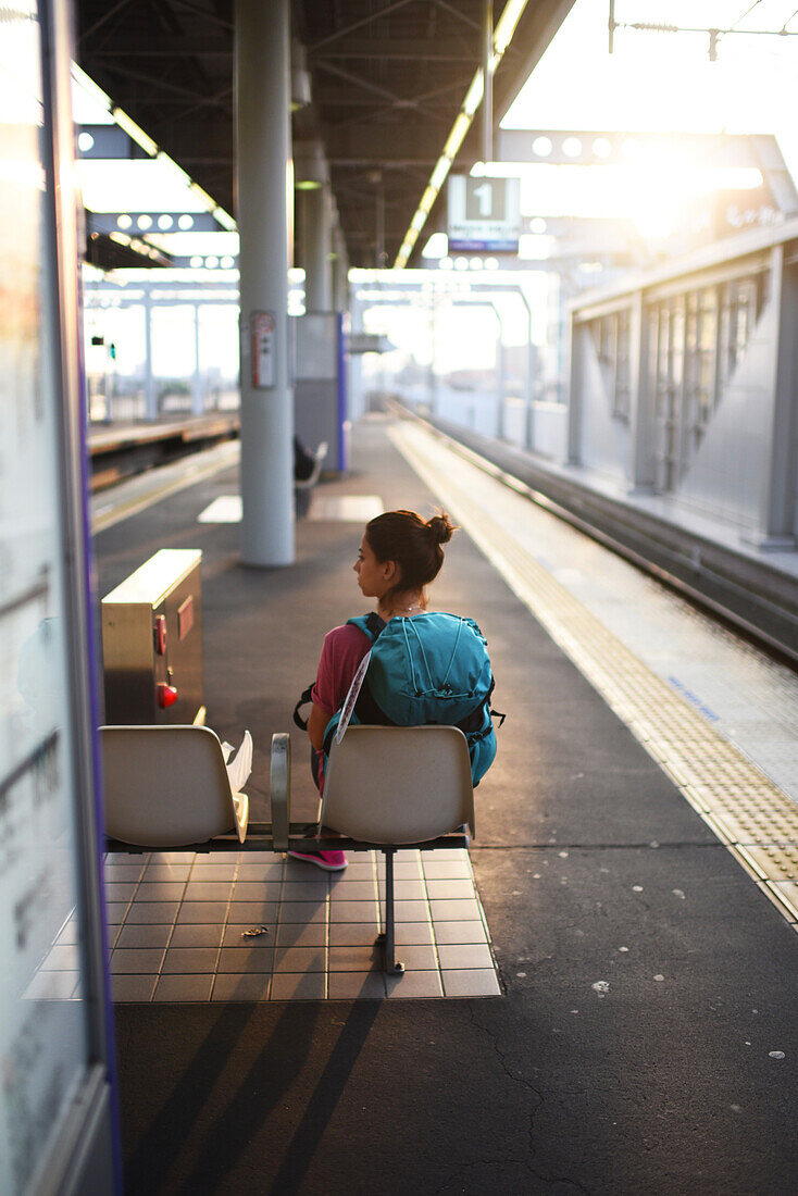 Young woman waits for transfer train to Kansai Airport, Japan