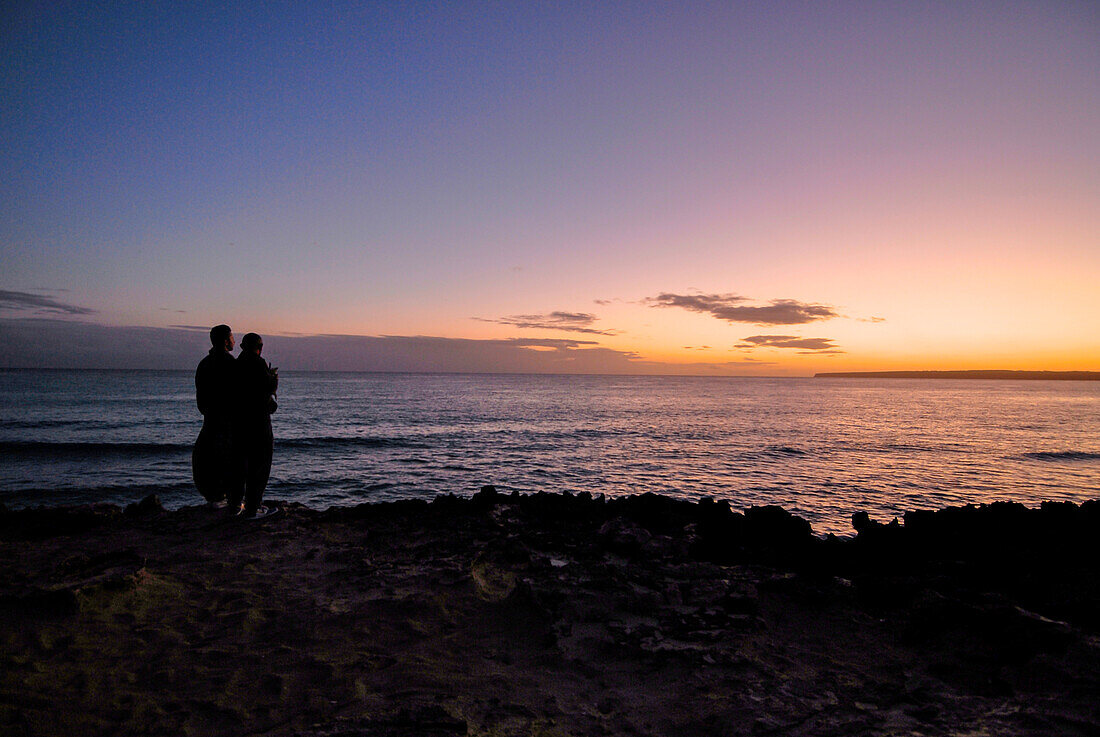 Ein Paar genießt einen wunderschönen Sonnenuntergang am Strand von Migjorn, Formentera