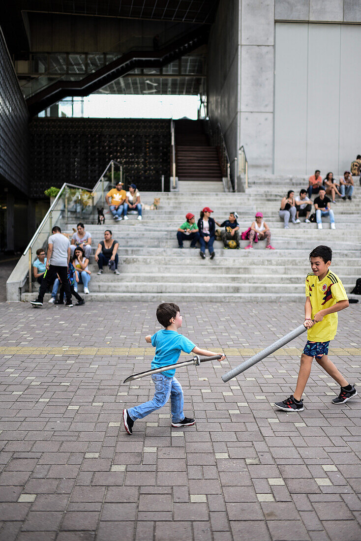 Kinder kämpfen mit Plastikschwertern vor dem Museum für moderne Kunst in Medellin (MAMM), Kolumbien
