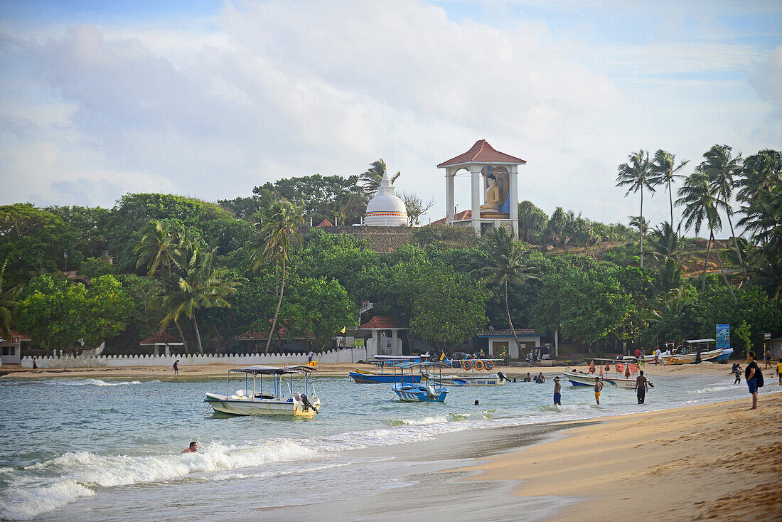 Einheimische und Touristen genießen einen sonnigen Tag am Strand von Unawatuna im Bezirk Galle, Sri Lanka
