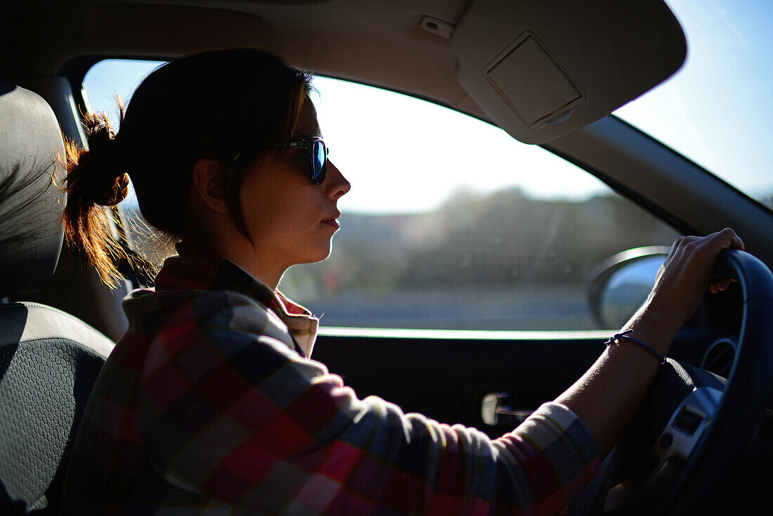 Junge Frau fährt Auto bei Sonnenuntergang