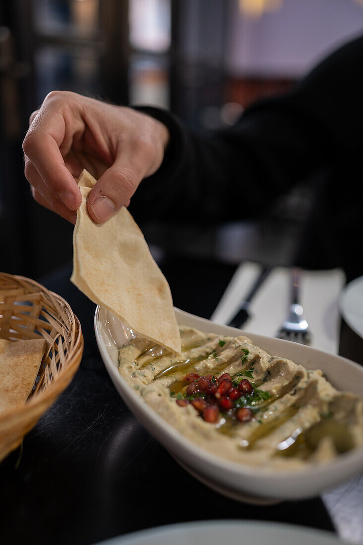 Männerhand beim Verzehr eines Hummus-Gerichts im Restaurant Mosaico, Zaragoza, Spanien