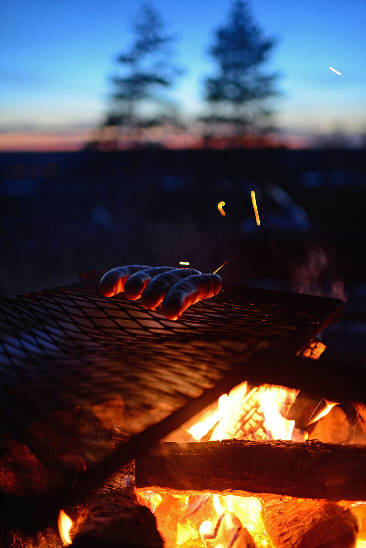 Würstchen und Kaffee auf dem Feuer gekocht. Motorschlittentour bei Sonnenuntergang mit Arctic Lifestyle, Rovaniemi, Lappland, Finnland