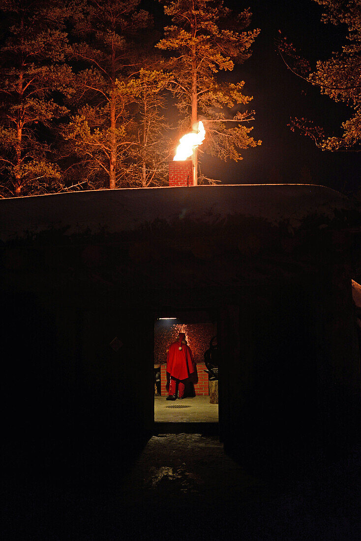 Junge Elfe wirft magisches Pulver ins Feuer. Kakslauttanen Arctic Resort in Saariselka, Finnland