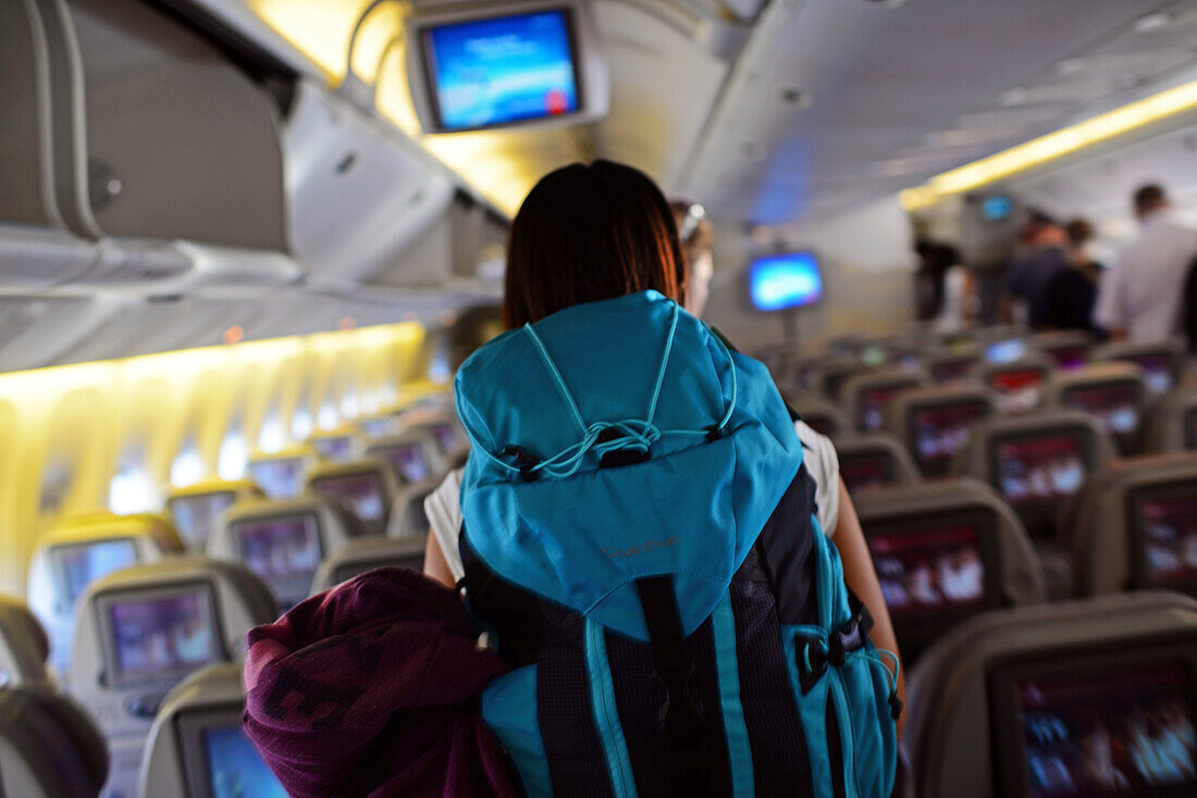Junge Frau betritt Flugzeug mit Rucksack