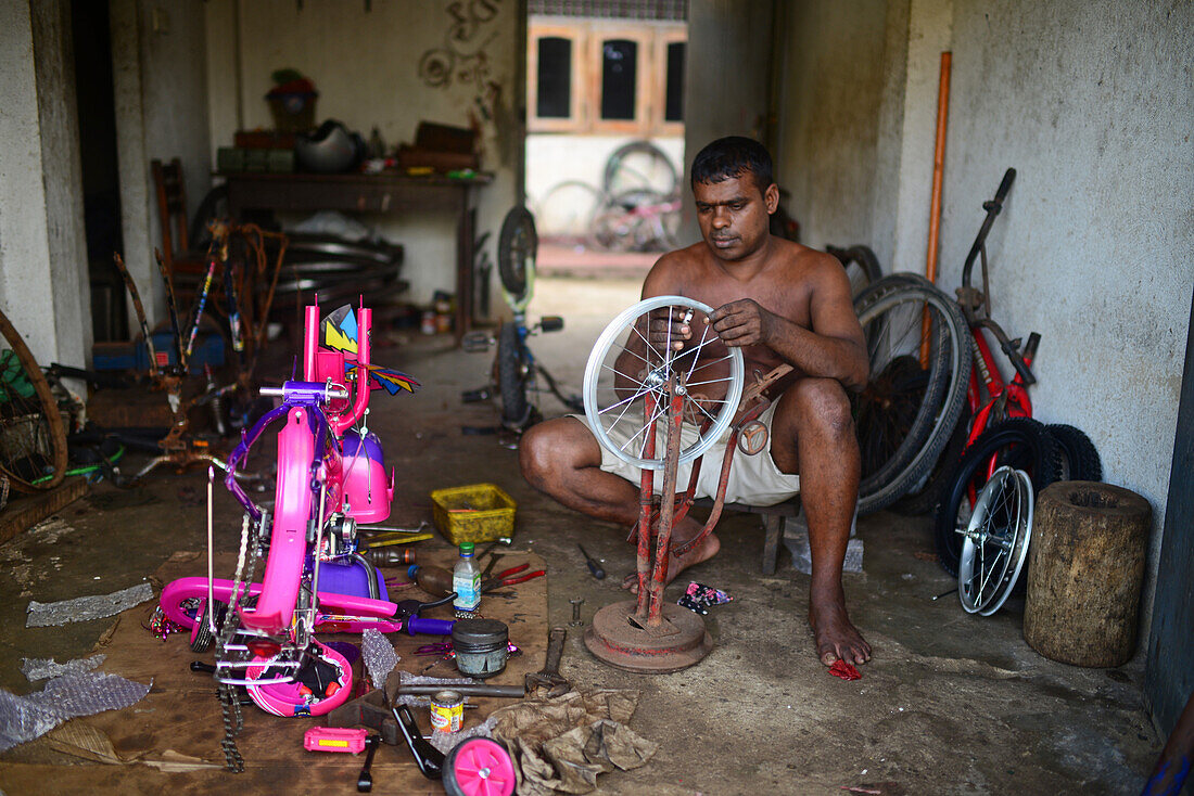 Mann repariert ein Fahrrad in einer Fahrradwerkstatt, Ahangama, Sri Lanka