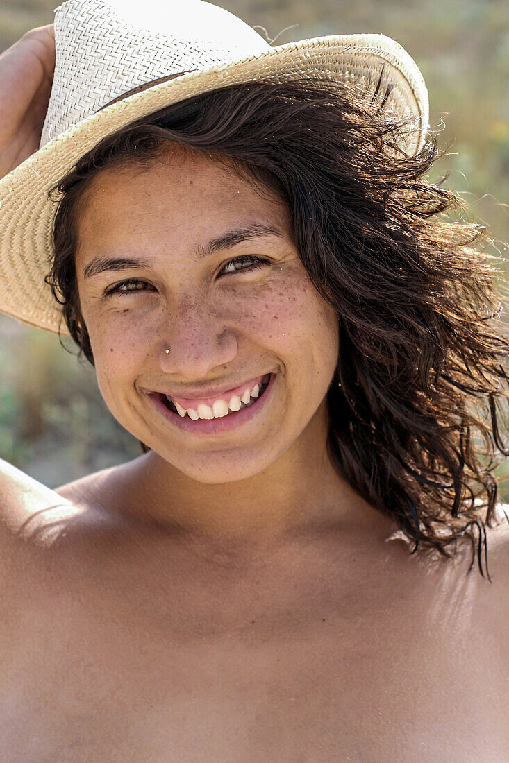 Porträt einer lächelnden brünetten jungen Frau mit gemischten Rassen am Strand von Formentera, Spanien
