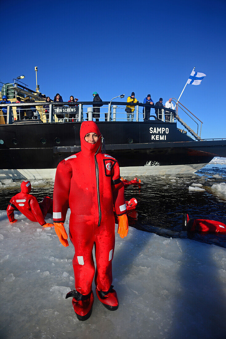 Junge Frau schwimmt im gefrorenen Meer während einer Kreuzfahrt mit dem Sampo Icebreaker, einem authentischen finnischen Eisbrecher, der zu einer Touristenattraktion in Kemi, Lappland, umgebaut wurde
