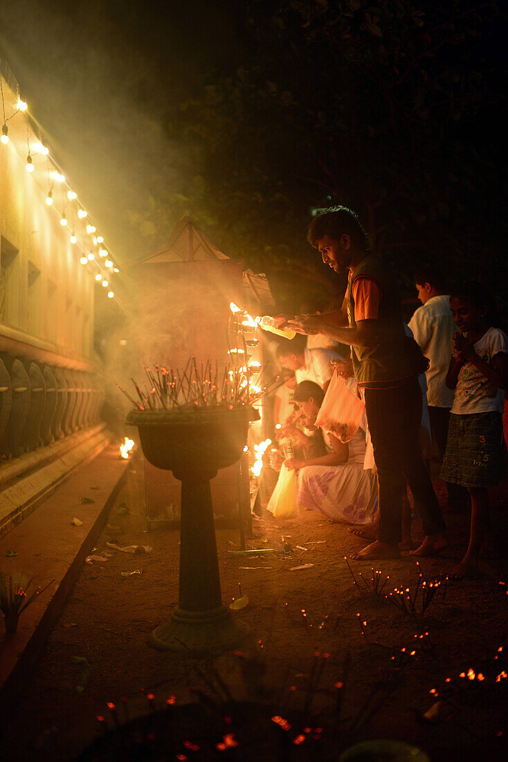 Menschen zünden Kerzen und Weihrauch als Opfergaben und Gebete im UNESCO-Weltkulturerbe Galle Fort an, während des Binara-Vollmond-Poya-Tages