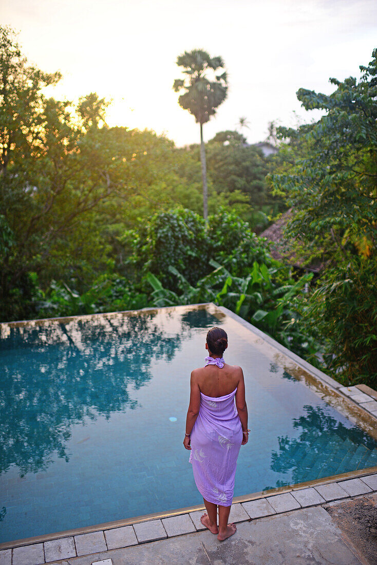 Young attractive woman enters an infinity edge swimming pool at The Dutch House, Galle, Sri Lanka