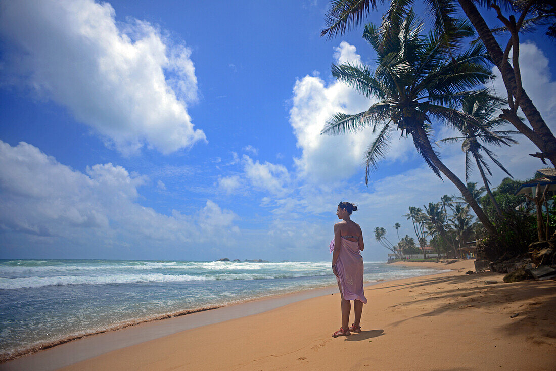 Young woman walking on Hikkaduwa beach at sunset, Sri Lanka