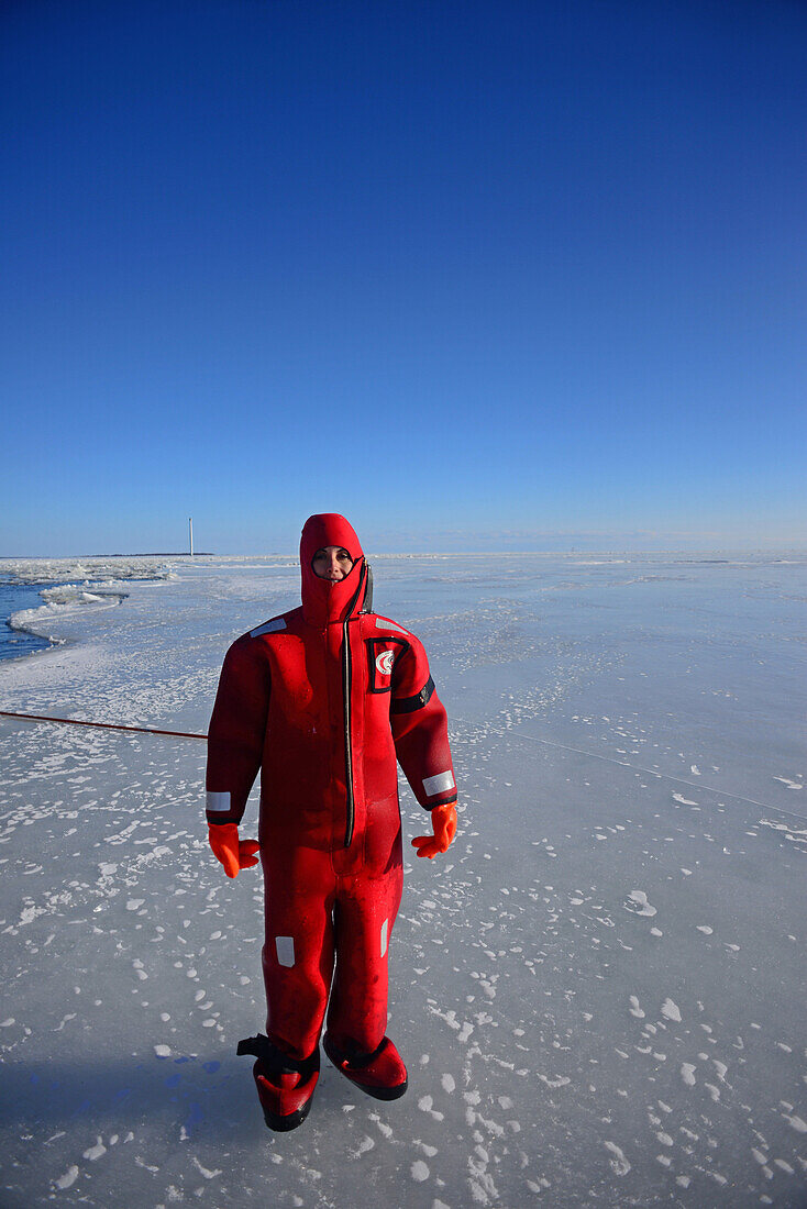 Junge Frau schwimmt im gefrorenen Meer während einer Kreuzfahrt mit dem Sampo Icebreaker, einem authentischen finnischen Eisbrecher, der zu einer Touristenattraktion in Kemi, Lappland, umgebaut wurde