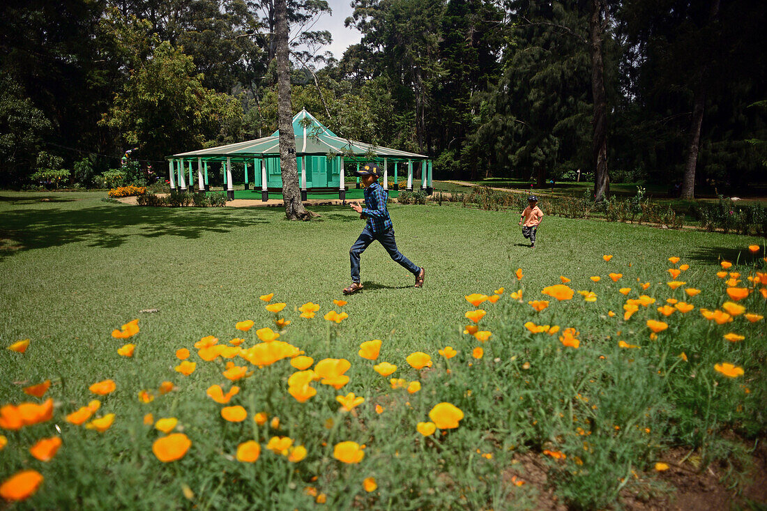 Zwei Kinder rennen und haben Spaß im Victoria Park, einem öffentlichen Park in Nuwara Eliya, Sri Lanka
