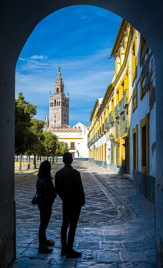 Junges Paar bewundert den Giralda-Turm vom Patio de Banderas-Platz aus, Sevilla, Spanien