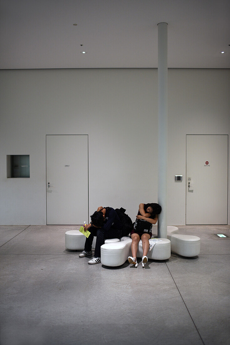 Erschöpftes Paar schläft auf dem Sofa im 21st Century Museum of Contemporary Art, Kanazawa, Japan
