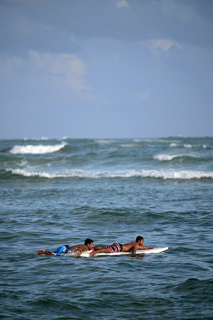 Zwei junge Männer rudern auf Brettern am Strand von Unawatuna, Sri Lanka