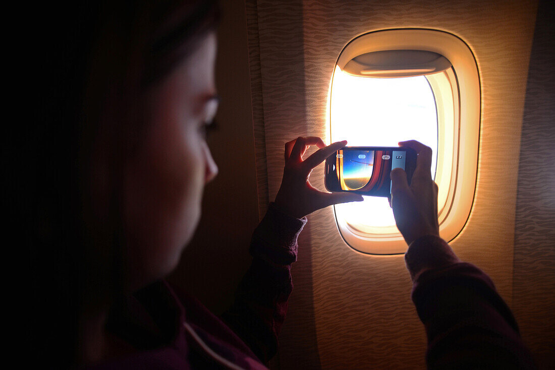 Junge Frau fotografiert während des Fluges durch das Fenster