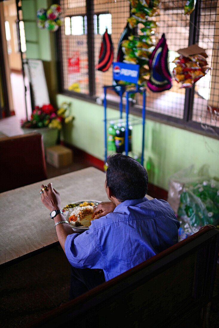 Mann isst in einem Bahnhofsrestaurant, Sri Lanka