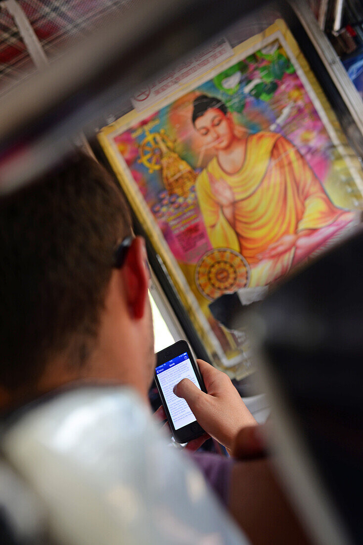 Young man using smartphone in bus, Sri Lanka