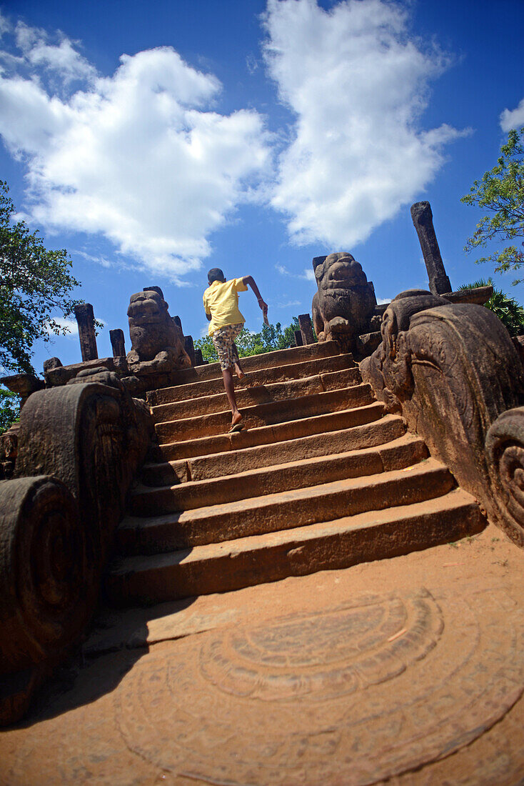 Junge rennt die Treppe in der Audienzhalle in der antiken Stadt Polonnaruwa, Sri Lanka, hinauf