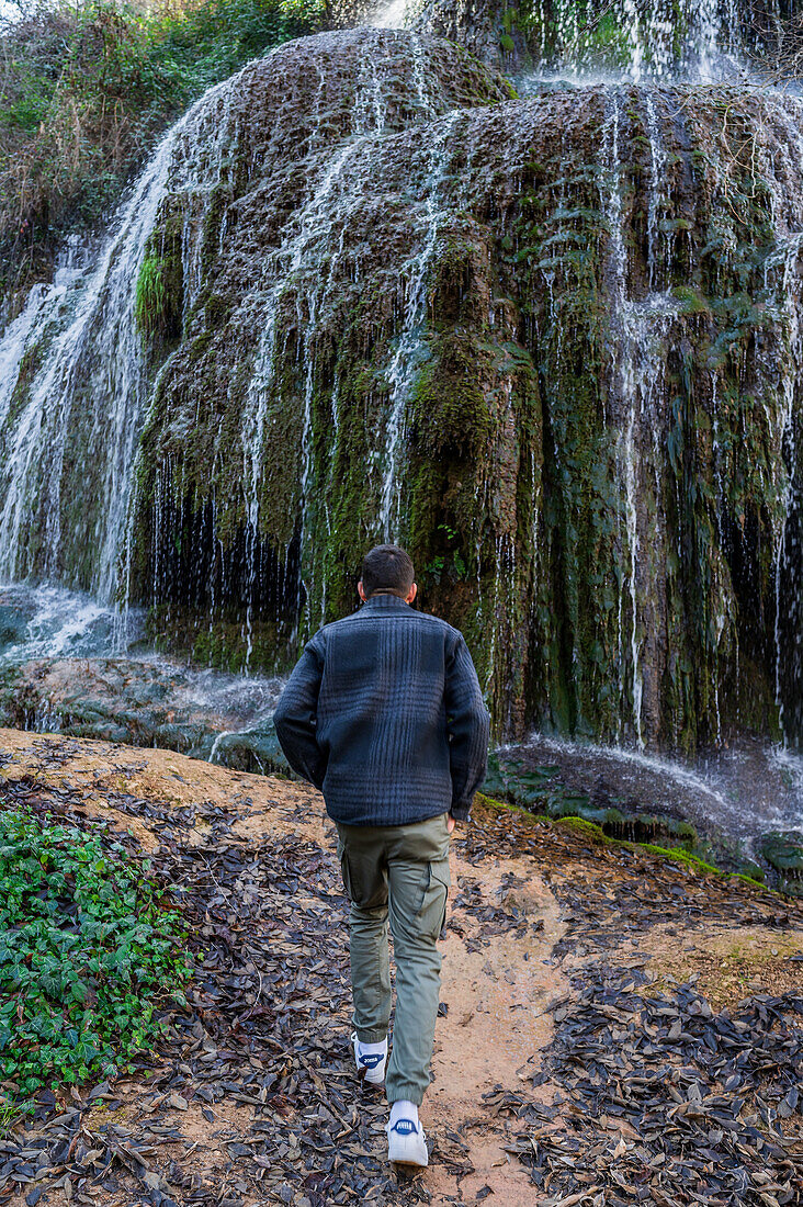 Junger Mann spaziert im Naturpark Monasterio de Piedra, der sich um das Monasterio de Piedra (Steinkloster) in Nuevalos, Zaragoza, Spanien, erstreckt