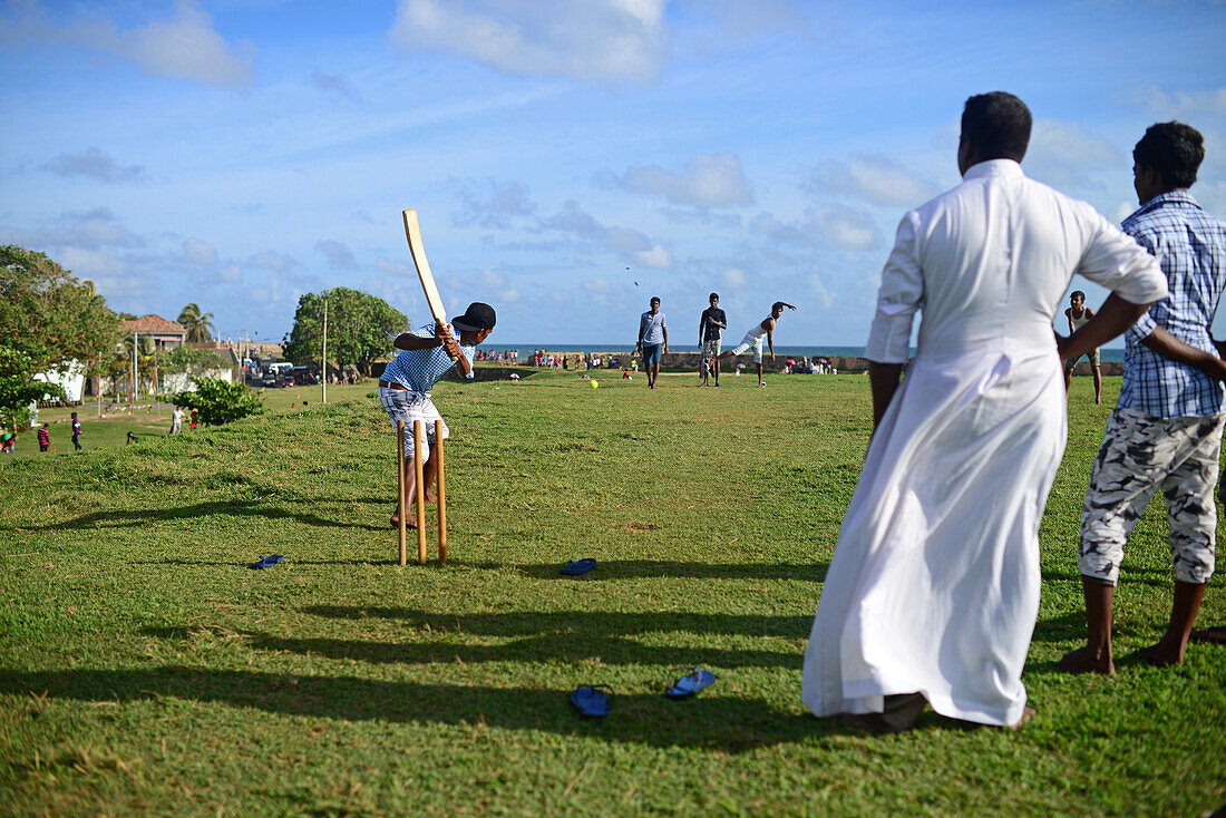 Junge Männer spielen Amateur-Cricket im UNESCO-Weltkulturerbe Galle Fort, während des Binara-Vollmond-Poya-Tages