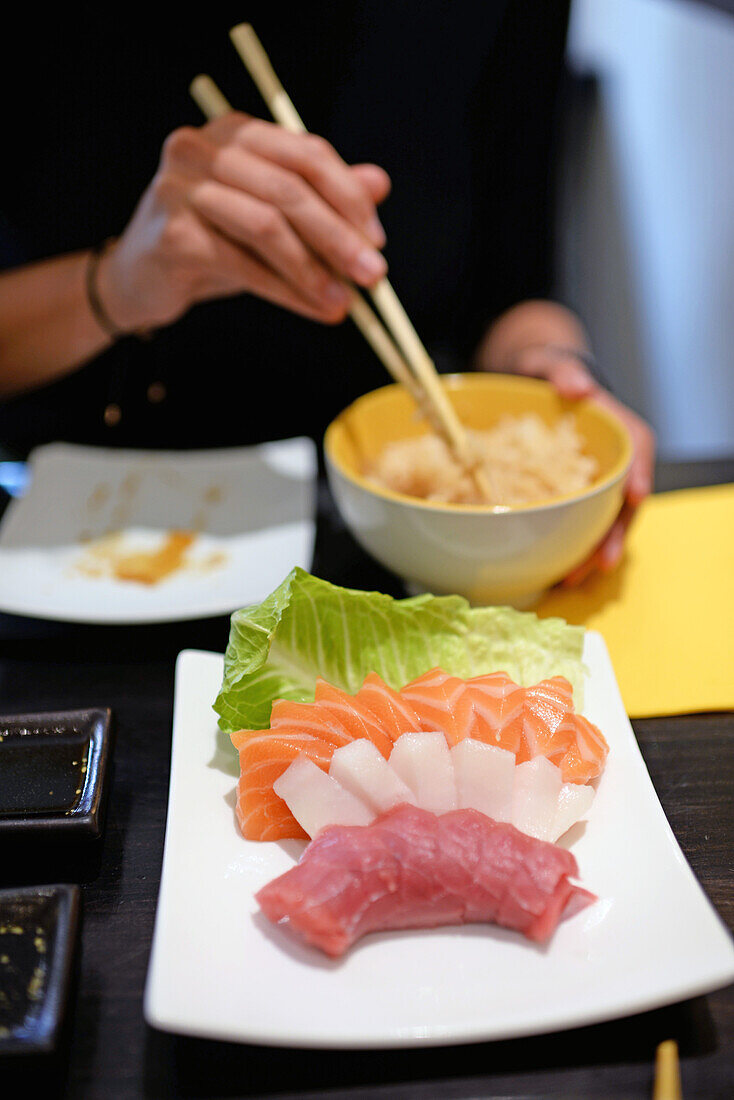 Woman eating white rice with sashimi