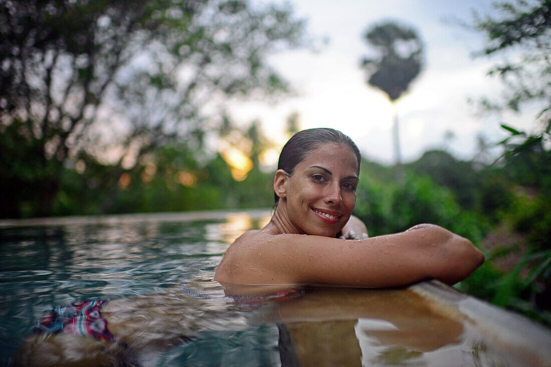 Young attractive woman enjoying a bath in the infinity edge swimming pool at The Dutch House, Galle, Sri Lanka