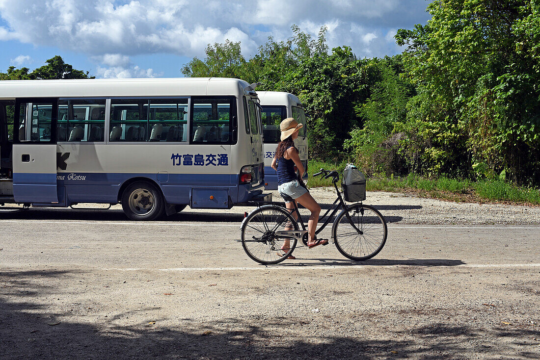 Frau fährt Fahrrad auf der Insel Taketomi, Präfektur Okinawa, Japan