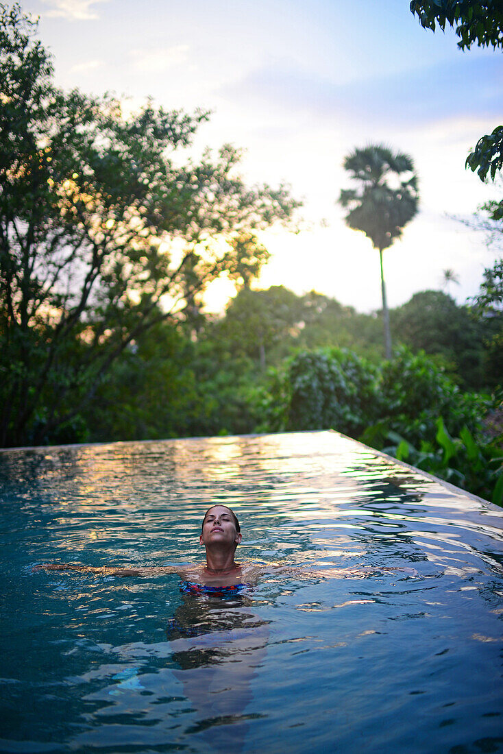 Young attractive woman enjoying a bath in the infinity edge swimming pool at The Dutch House, Galle, Sri Lanka