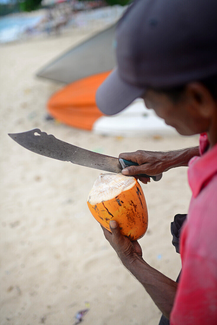 Kokosnussverkäufer schneidet die Kokosnuss am Strand von Unawatuna, Sri Lanka