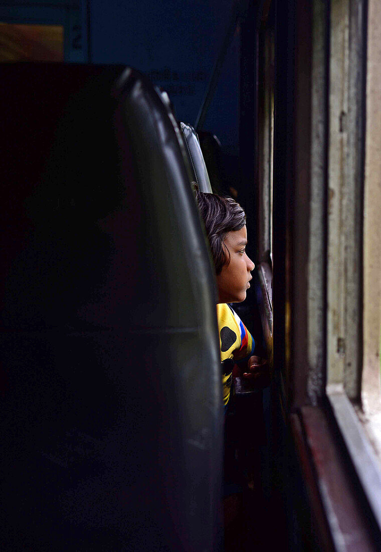 Young girl looking through train window, Sri Lanka