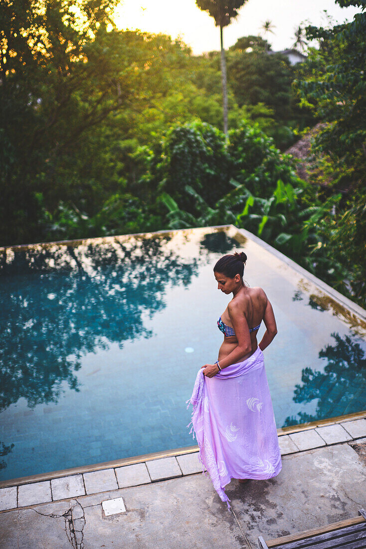 Young attractive woman enters an infinity edge swimming pool at The Dutch House, Galle, Sri Lanka