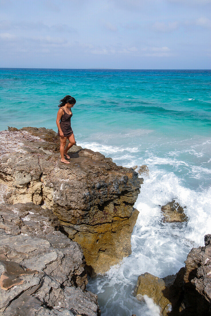 Junge attraktive brünette Frau am Rande einer Klippe an der Küste der Mittelmeerinsel Formentera auf den Balearen, Spanien