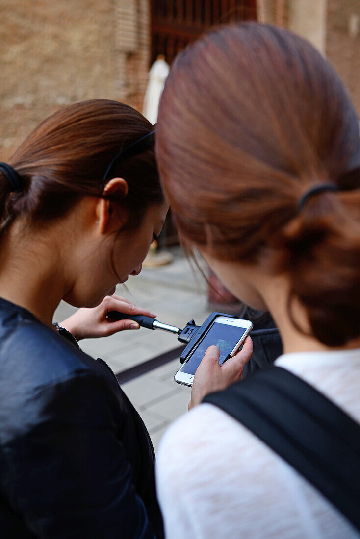 Asiatische Touristen benutzen ein Mobiltelefon in der Alhambra, einem Palast- und Festungskomplex in Granada, Andalusien, Spanien