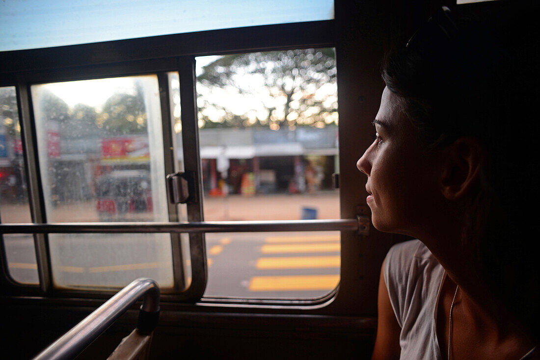 Young woman watches through window in bus, Sri Lanka