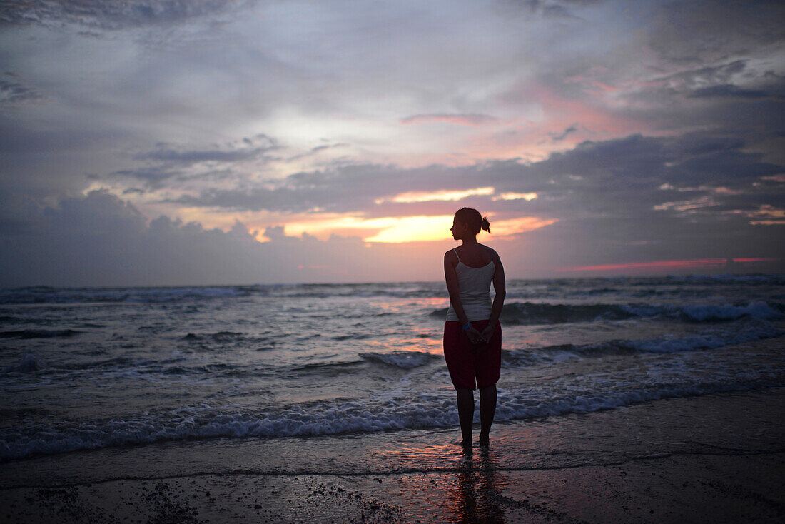 Junge Frau genießt den Sonnenuntergang am Strand von Hikkaduwa, Sri Lanka