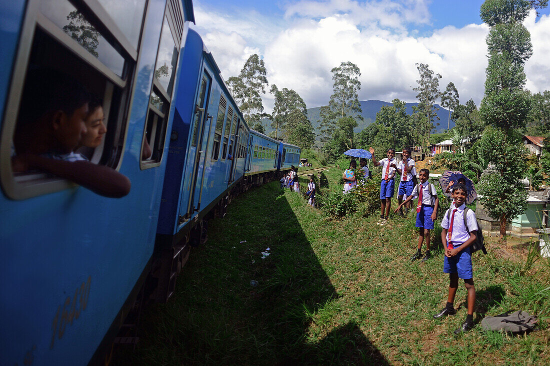 Schuljungen erfreuen sich an der Vorbeifahrt eines Zuges. Zugfahrt von Kandy nach Nuwara Eliya, Sri Lanka